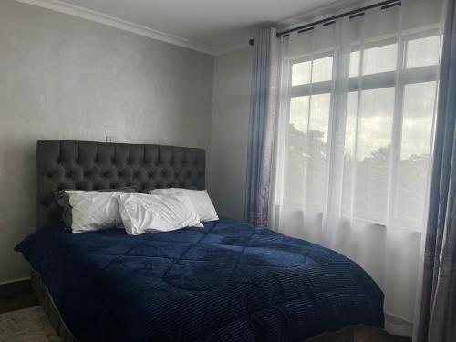 a bedroom with a bed with a blue comforter and a window at Family friendly apartment in Nairobi