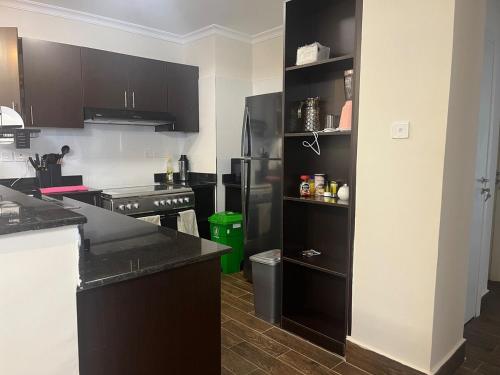a kitchen with black cabinets and a black refrigerator at Family friendly apartment in Nairobi