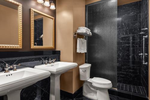 a bathroom with two sinks and a toilet and a shower at Hotel Mazarin in New Orleans