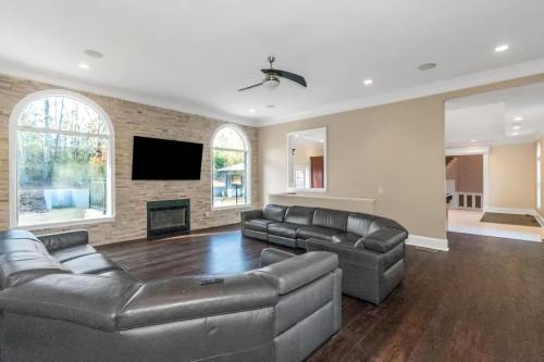 a living room with leather furniture and a flat screen tv at The Panola Mansion - Indoor Pool & Pavilion in Stockbridge