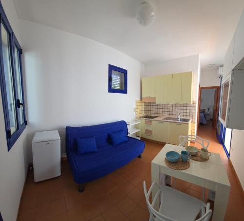 a living room with a blue couch and a kitchen at La Casa Di Lele in Torre dell'Orso