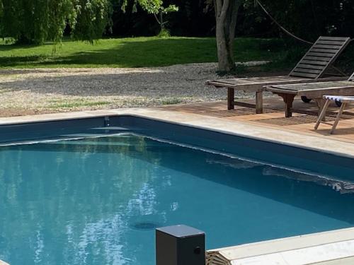 - une piscine avec une table de pique-nique et un banc dans l'établissement Charmante Longère Piscine chauffée 8x4 Terrasse, Mer & Campagne Normandie, à Saint-Étienne-la-Thillaye