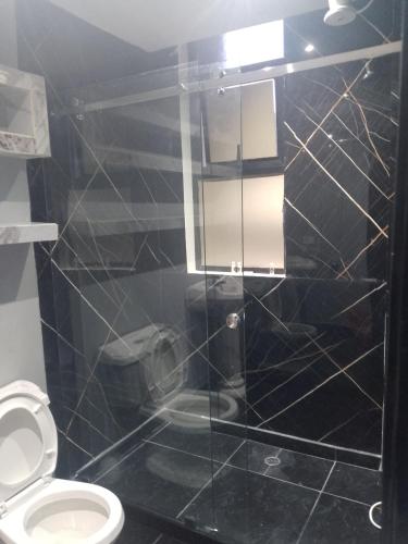 a bathroom with a toilet and a black tiled wall at Hotel Gool de Guerrón in Quito