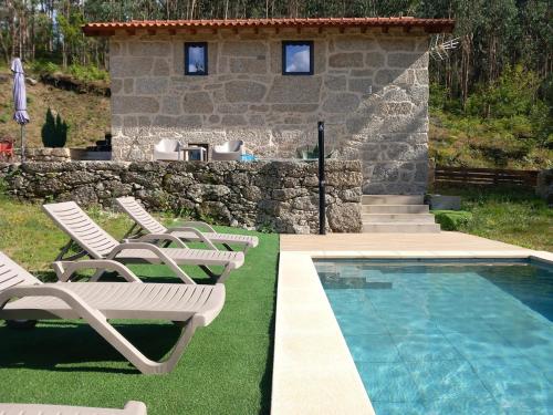 a group of chairs and a swimming pool next to a house at Casa do Oitão in Vieira do Minho