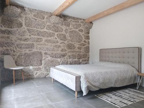 a bedroom with a bed and a stone wall at Casa do Oitão in Vieira do Minho