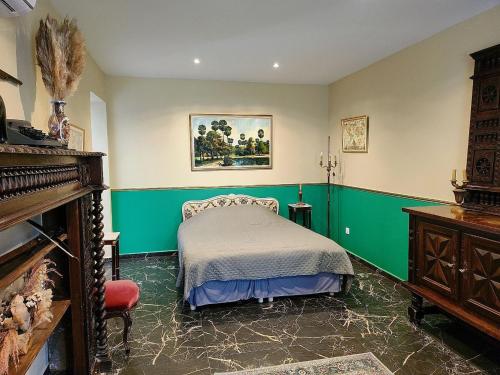 une chambre avec un lit, des murs verts et un piano dans l'établissement La Perchonniere, à Mamers