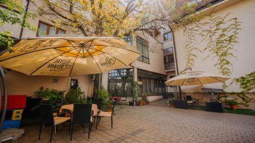 two tables and umbrellas in front of a building at Boutique Hotel Maraton in Košice