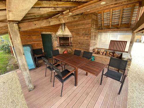 une table et des chaises en bois sur une terrasse avec une cheminée dans l'établissement Aux Premières Loges - Gîte de charme proche du circuit, à Arnage