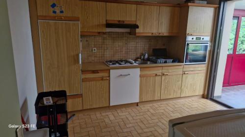 une cuisine avec des armoires en bois et un four blanc dans l'établissement Maison entière 5 min de rennes, à Laillé