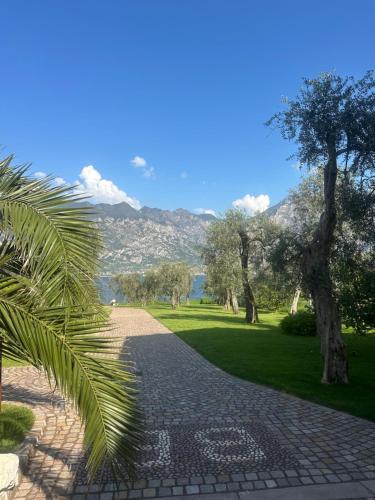 a cobblestone path in a park with trees and a mountain at B&B Casa Benamati by Kelly in Malcesine