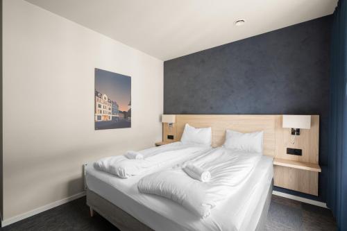 a bedroom with a large bed with white sheets at BREEZE Hotel Victoria - Self-Service in Bergen