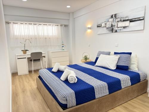 a bedroom with a bed with blue and white sheets at Encantador apartamento com piscina in Costa da Caparica