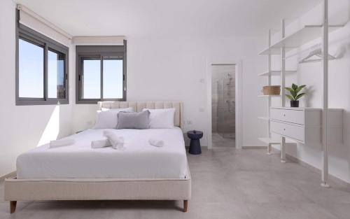 - une chambre blanche avec un grand lit et une commode dans l'établissement נופש משפחתי באילת עם נוף לים האדום, à Eilat