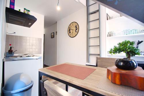 a kitchen with a table and a clock on the wall at Petit Duplex Lumineux, hyper centre à 2 pas du port, Intendance Luxury Host in Cherbourg en Cotentin