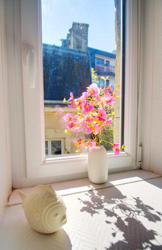 a vase sitting on a window sill with flowers in it at Petit Duplex Lumineux, hyper centre à 2 pas du port, Intendance Luxury Host in Cherbourg en Cotentin