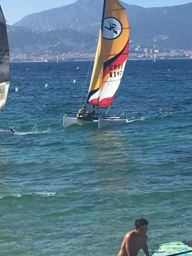 un homme sur la plage avec un voilier dans l'eau dans l'établissement appartement LE CLAN, à Bastelicaccia