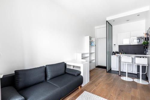 un salon avec un canapé noir et une cuisine dans l'établissement Studio Bastille, à Paris