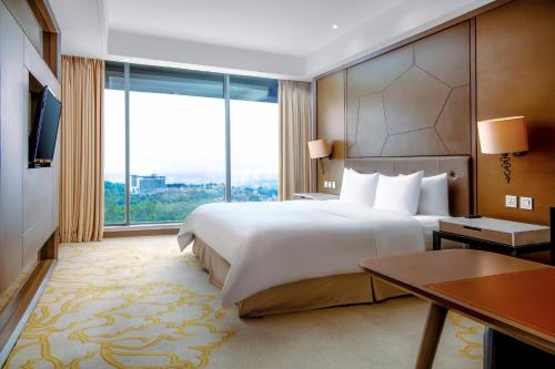 a hotel room with a large bed and a large window at InterContinental Bandung Dago Pakar by IHG in Bandung