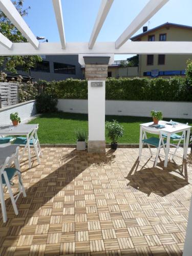 a patio with two tables and a white pergola at H5-5H Luxury Room in Maranello