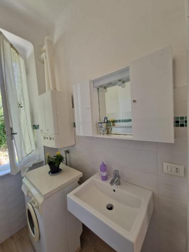a white bathroom with a sink and a mirror at Il Paradiso di Adriana in Bonassola
