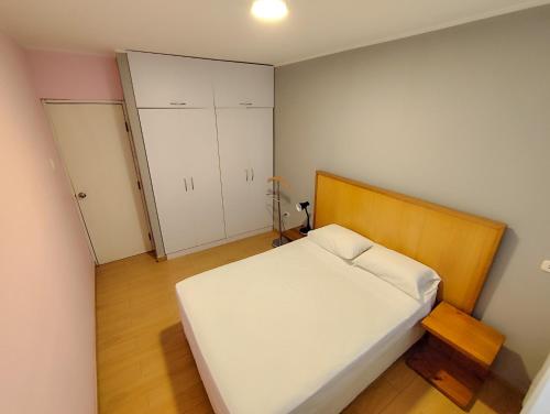 a small bedroom with a white bed and white cabinets at Apartamento Limas Airport in Lima