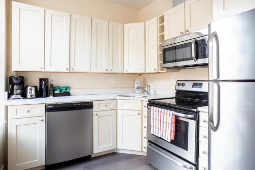 a kitchen with white cabinets and a stainless steel refrigerator at Prime Boston Fidi L Shaped Studio in Boston