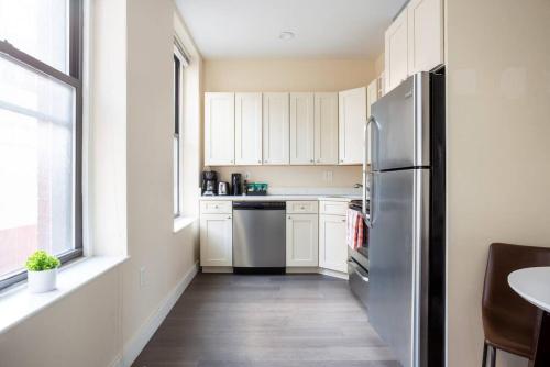 a kitchen with white cabinets and a stainless steel refrigerator at Prime Boston Fidi L Shaped Studio in Boston