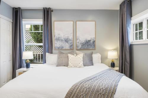 a bedroom with a large white bed with two windows at Coastal Dream Heated Pool Near Beach and Disney in Long Beach