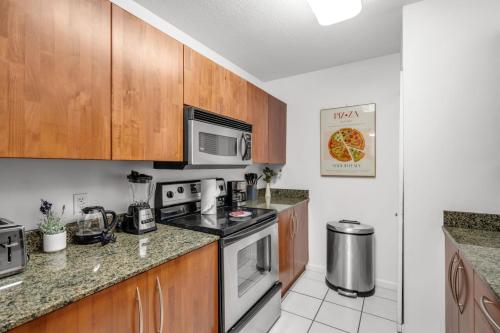 a kitchen with stainless steel appliances and wooden cabinets at Enjoy Brickell Living 2 BR Retreat With Free Parking in Miami