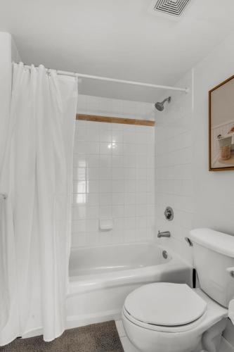 a white bathroom with a toilet and a bath tub at Enjoy Brickell Living 2 BR Retreat With Free Parking in Miami