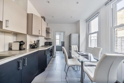 a kitchen with a table and white chairs in a kitchen at Amazing One Bed Flat Wimbledon in London
