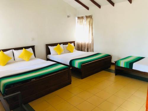 a bedroom with two beds with yellow and green pillows at Tranquil Garden Nuwara Eliya in Nuwara Eliya