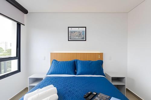 a bedroom with a bed with a blue comforter at Apartamentos modernos próximo ao Jardim Botanico e à Rodoviária in Curitiba