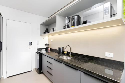 a kitchen with white cabinets and a sink at Apartamentos modernos próximo ao Jardim Botanico e à Rodoviária in Curitiba