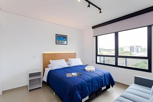 a bedroom with a blue bed and a chair at Apartamentos modernos próximo ao Jardim Botanico e à Rodoviária in Curitiba