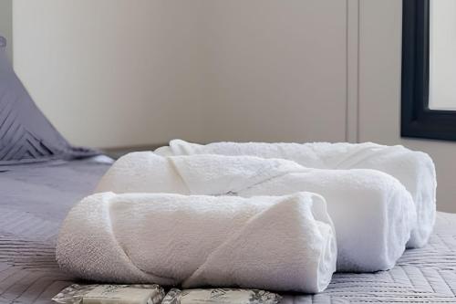 a pile of white towels on a bed at Apartamentos modernos próximo ao Jardim Botanico e à Rodoviária in Curitiba