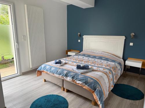 une chambre avec un lit aux murs bleus et une fenêtre dans l'établissement Les Oliviers, à Fort-Mahon-Plage