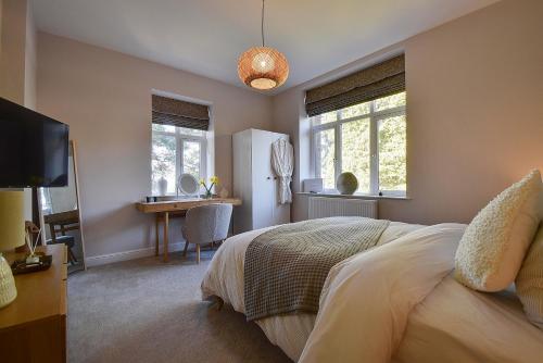 a bedroom with a bed and a desk and a television at Modern flat nestled in the Malvern Hills Worcestershire in Great Malvern