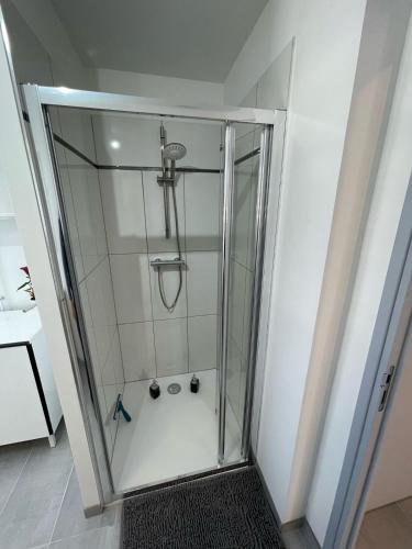 une douche avec une porte vitrée dans une salle de bain dans l'établissement L'escapade Confort Saint-Quentinoise, à Saint-Quentin