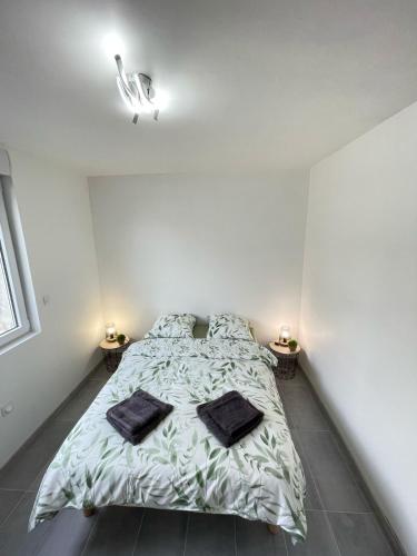 une chambre avec un lit avec deux oreillers dessus dans l'établissement L'escapade Confort Saint-Quentinoise, à Saint-Quentin