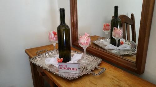 zwei Flaschen Wein auf einem Tisch vor einem Spiegel in der Unterkunft Acropolis Hotel in Korinthos