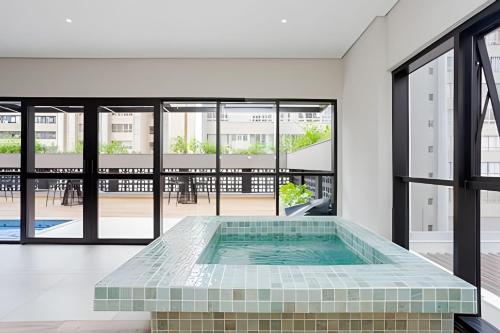 einen Pool in der Mitte eines Zimmers mit Fenstern in der Unterkunft Apartamentos para 5 pessoas com Piscina e Academia no Centro in Curitiba