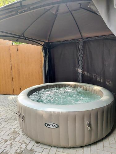a hot tub with an umbrella on a patio at Vikendica Drinski mir in Loznica