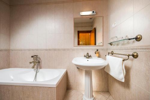 ein Badezimmer mit einem Waschbecken und einer Badewanne in der Unterkunft Ózoon Hotel in Nyíregyháza