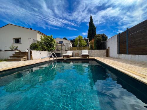 a swimming pool with a wooden deck and blue water at Le temps de vivre in Mormoiron