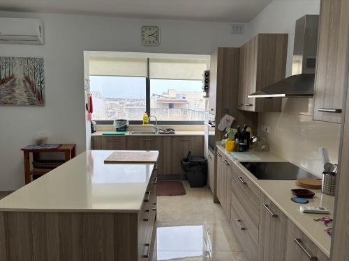 eine Küche mit weißen Arbeitsflächen und einem großen Fenster in der Unterkunft Home Vibes II in L-Armier