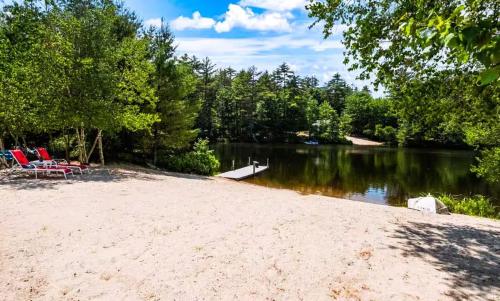a sandy beach next to a lake with chairs at NEW Beautiful Lakefront Home! 500ft of Waterfront! in Wakefield