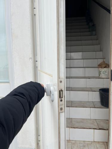 a persons hand opening a door with stairs in the background at Quarto da casa da avó in Cercal