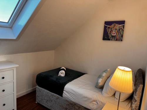 a bedroom with a bed with a lamp and a painting at Wellesley Apartment in Leven-Fife