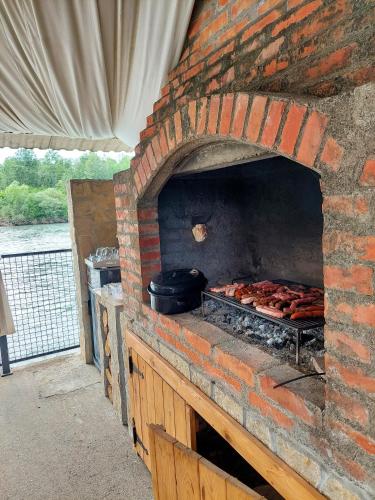 a brick oven with meat and a pot on it at Vikendica Drinski mir in Loznica